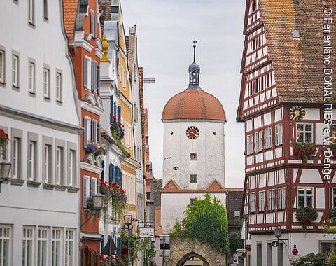 Stadt Oettingen Straße mit historischen Gebäuden und einem Turm mit Uhr in der Mitte, umgeben von Fachwerkhäusern.