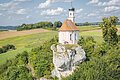 Ferienland Donau-Ries Shooting 2021 Kleine Kirche mit Zwiebelturm auf einem Felsen, umgeben von grünen Feldern und Bäumen.