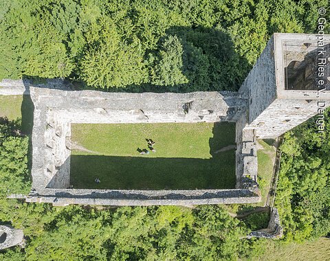 Burgruine Niederhaus von oben Luftaufnahme einer rechteckigen Burgruine mit einem Turm, umgeben von dichtem Wald.