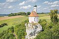 Ferienland Donau-Ries Shooting 2021 Kleine Kirche mit Zwiebelturm auf einem Felsen, umgeben von grünen Feldern und Bäumen.